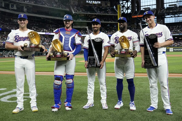 Texas Rangers' Nathaniel Lowe, from left, Jonah Heim, Marcus Semien, Adolis Garcia and Corey Seager, right, stand holding their respective Gold Glove and Silver Slugger awards during a ceremony before a baseball game against the Oakland Athletics in Arlington, Texas, Wednesday, April 10, 2024. (AP Photo/Tony Gutierrez)