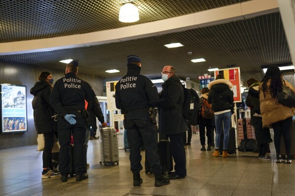 FILE -Police officers talk to passengers arriving from abroad, at Gare du Midi international train station in Brussels, Tuesday, Jan. 19, 2021. Belgium acknowledges that its major rail gateway has become a festering sore of drug abuse, poverty and violence. The Brussels Midi Station is a major stain on a nation preparing to take on the presidency of the European Union next year. (AP Photo/Francisco Seco, File)