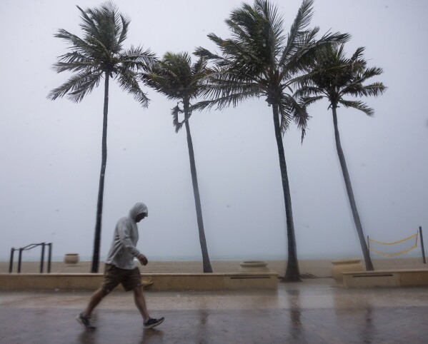 am Mittwoch, 12. Juni 2024, in Hollywood, Florida.  (Matthias J. Ochner/AP über Miami Herald) Ein Mann geht den Hollywood Beach Broadwalk entlang, während heftiger Regen Teile Südfloridas erschüttert.