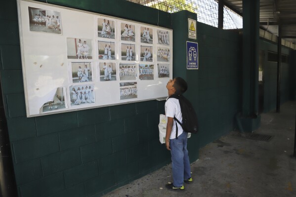 Alex Recinos, 10, looks at a bulletin displayed with photos of inmates to see if his mom is pictured, at the food drop-off entrance of the Apanteos women's prison, in Santa Ana, El Salvador, Wednesday, Jan. 31, 2024. (AP Photo/Salvador Melendez)