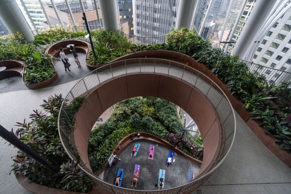 A yoga class takes place on the Green Oasis botanical promenade at the CapitaSpring's skyscraper in Singapore, Thursday, July 20, 2023. The public green space spirals between levels 17 – 20 surrounded by downtown high-rises and features roughly 80,000 plants. (AP Photo/David Goldman)