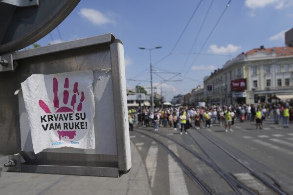 A sticker reads "You have blood on your hands" is attached to a traffic sign as Serbia's protesting university students stand in silence to commemorate the 15 victims killed after a railway concrete canopy fell in November and demanding an immediate snap election after leading months of anti-corruption demonstrations, in Belgrade, Serbia, Tuesday, May 6, 2025. (AP Photo/Darko Vojinovic)