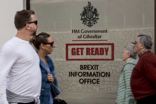 FILE - People walk past a Brexit information office at the British territory of Gibraltar, on Jan. 31, 2020. British and Spanish foreign ministers are to meet in Brussels on Friday April 12, 2024 in a bid to take a giant leap forward on talks over the status of the disputed territory of Gibraltar following Britain's exit from the European Union. All sides are eager to clinch a deal before European elections in June which could set the clock back. Britain left the European Union in 2020 with the relationship between Gibraltar and the bloc unresolved. (AP Photo/Javier Fergo, File)