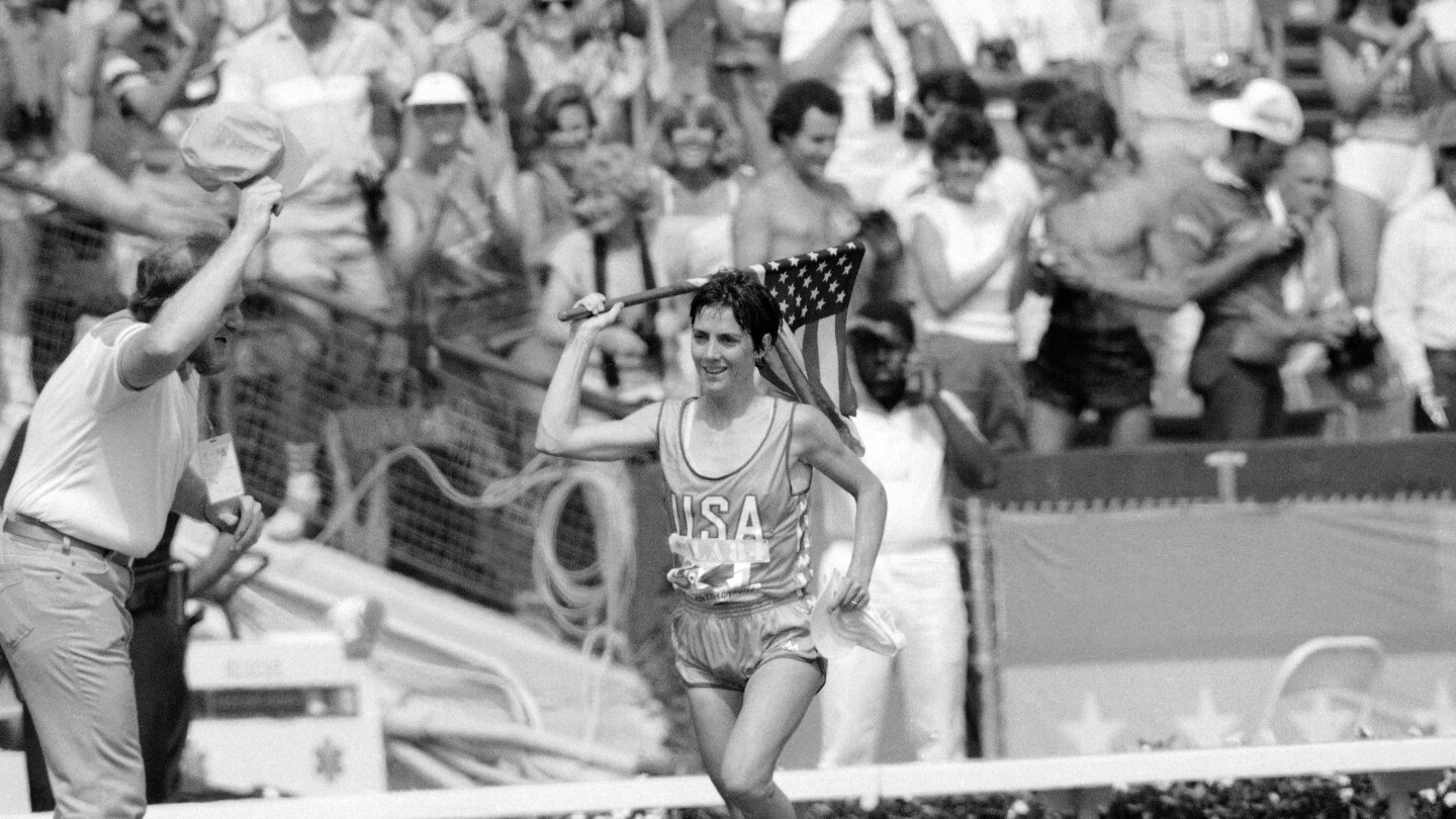 FILE - Twenty-seven-year-old Joan Benoit of Freeport, Maine, waves the American flag enthusiastically on Aug. 5, 1984, in Los Angeles after finishing the first-ever Olympic women's marathon in the fastest-ever time for that distance. 2.24:52 for the 26-mile, 385-yard course. (AP Photo/Dieter Endlicher, File)