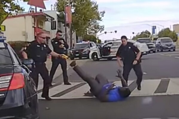 In this image from video provided by the San Mateo County Sheriff's Office, Chinedu Okobi lies on the ground in Millbrae, Calif., on Oct. 3, 2018, during a police encounter where officers used a stun gun, chemical spray, baton strikes and prone restraint in a sequence of rapid escalation. San Mateo County deputies told the district attorney they were reacting to what they perceived as Okobi's "superhuman strength." (San Mateo County Sheriff's Office via AP)