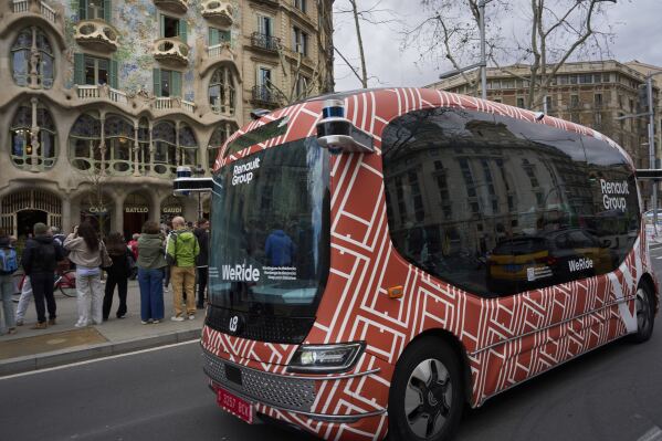 A driverless mini-bus, presented by WeRide and Renault Group, drives by Casa Batlló, designed by Antoni Gaudí, in Barcelona downtown, Wednesday, March 12, 2025. (AP Photo/Emilio Morenatti)