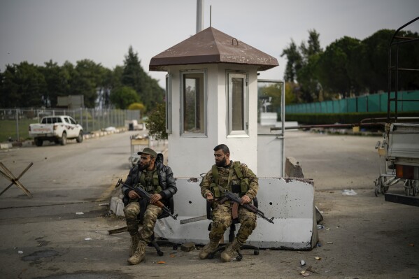 Syrian fighters guard the entrance of the Lakatia civilian airport located in the town of Hmeimim, southeast of Latakia, Syria, Monday Dec. 16, 2024.(AP Photo/Leo Correa, File)