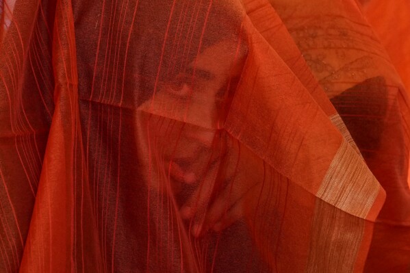 A Kashmiri Muslim bride looks through her veil during a mass wedding in Srinagar, Indian controlled Kashmir, Thursday, June 15, 2023. Mass weddings in India are organized by social organizations primarily to help economically backward families who cannot afford the high ceremony costs as well as the customary dowry and expensive gifts that are still prevalent in many communities. (APPhoto/Mukhtar Khan)