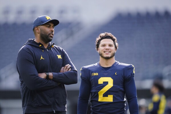Michigan offensive coordinator Sherrone Moore, left, speaks with running back Blake Corum during NCAA college football practice Saturday, Dec. 30, 2023, in Inglewood, Calif. Alabama is scheduled to play against Michigan on New Year's Day in the Rose Bowl, a semifinal in the College Football Playoff. (AP Photo/Ryan Sun)