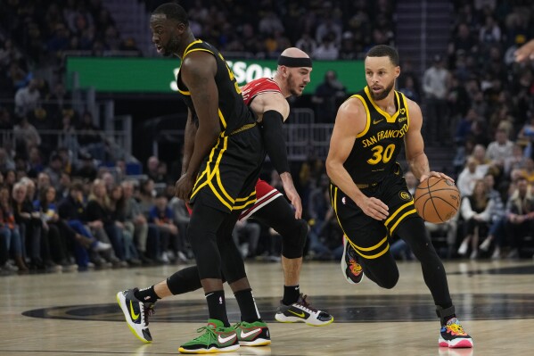 Golden State Warriors guard Stephen Curry, right, moves around a screen by Draymond Green on Chicago Bulls forward Alex Caruso, center, during the first half of an NBA basketball game Thursday, March 7, 2024, in San Francisco. (AP Photo/Godofredo A. Vásquez)