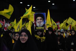 FILE - A Hezbollah supporter holds up a picture of the leader of Lebanon's Iran-backed Hezbollah leader Sayyed Hassan Nasrallah, during a ceremony to mark the third anniversary of the assassination of Iran's Quds force General Qassem Soleimani, who was killed in a U.S. drone strike in Baghdad, in the southern Beirut suburb of Dahiyeh, Lebanon, on Jan. 3, 2023. Lebanon's militant Hezbollah group on Tuesday, Jan. 10, 2023 condemned the cartoons published recently by the French satirical magazine Charlie Hebdo that mocked Iran's ruling clerics and urged France to punish the publication. (AP Photo/Bilal Hussein, File)