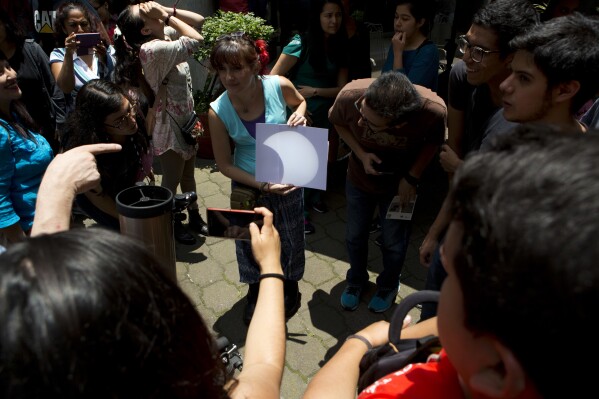 FILE - A telescope projects an image of a partial solar eclipse onto a piece of paper, at the Astronomy Institute on the campus of the National Autonomous University of Mexico, in Mexico City, Monday, Aug. 21, 2017. On April 8, 2024, the sun will pull another disappearing act across parts of Mexico, the United States and Canada, turning day into night for as much as 4 minutes, 28 seconds. (AP Photo/Rebecca Blackwell, File)