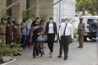 Mrs. World 2019 Caroline Jurie, center, leaves a police station after obtaining bail in Colombo, Sri Lanka, Thursday, April 8, 2021. Jurie's decision to remove the crown from the the winning Mrs. Sri Lanka contestant on stage moments after the winner was announced, because of claims she was a divorcee, drew widespread social media condemnation.  The winner Pushpika de Silva who was crowned again later had complained to police that her head was wounded when the clips of her crown were removed by Jurie. (AP Photo/Eranga Jayawardena)