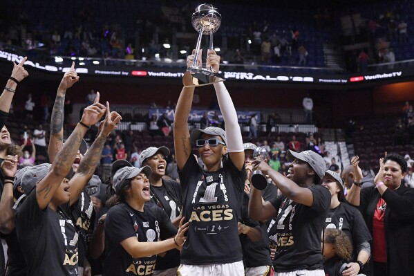 FILE - Las Vegas Aces' A'ja Wilson holds up the championship trophy as she celebrates with her team their win in the WNBA basketball finals against the Connecticut Sun, Sunday, Sept. 18, 2022, in Uncasville, Conn. The two-time defending WNBA champion Las Vegas Aces are favored to win the title again. They return their core four players to the roster from a team that became the first in more than 20 years to repeat as champions. (AP Photo/Jessica Hill, File)