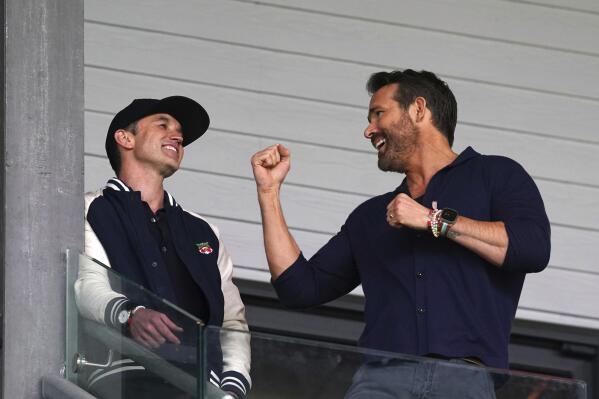 Wrexham co-owners Rob McElhenney, left, and Ryan Reynolds in the stands during the National League soccer match between Wrexham and Boreham Wood at The Racecourse Ground, in Wrexham, Wales, Saturday April 22, 2023. (Martin Rickett/PA via AP)