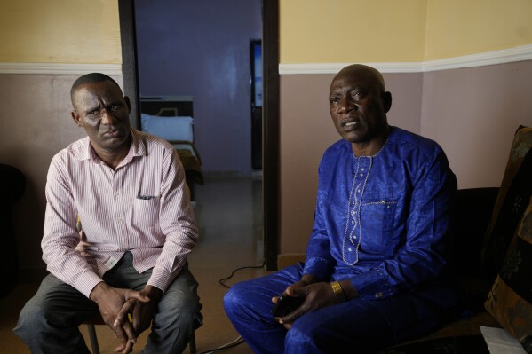 Pius Orofin, a deck operator aboard the Trinity Spirit oil ship, left, and Patrick Aganyebi, a maintenance operator, sit for an interview in Okitipupa, Nigeria, on Monday, Sept. 5, 2022. Not long after being hospitalized from the injuries they sustained escaping the fire on the Trinity Spirit, Aganyebi and Orofin learned they were being sent to jail, accused of conspiring to commit “Murder, Arson, and Malicious Damage,” according to charging documents. (AP Photo/Sunday Alamba)