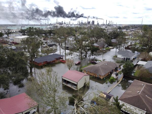 FILE - Homes near Norco, La., are surrounded by floodwater as refineries continue to flare the day after Hurricane Ida hit southern Louisiana, Aug. 30, 2021. Environmental and climate justice advocates from across the United States are decrying the court's 6-3 ruling on Thursday, June 30, 2022, saying it will be felt most by communities of color and poor communities, which are located near power plants at higher percentages than the national average. (Chris Granger/The Times-Picayune/The New Orleans Advocate via AP, File)