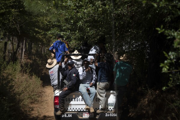 Locals ride in a National Guard truck in search of unlicensed water intakes and irrigation holding ponds that irrigate avocado and berry orchards during a drought in the mountains of Villa Madero, Mexico, Wednesday, April 17, 2024. Subsistence farmers and activists from the Michoacan town of Villa Madero organized teams to go into the mountains and rip out illegal water pumps and breach unlicensed irrigation holding ponds. (AP Photo/Armando Solis)