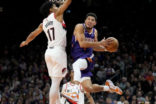 Phoenix Suns guard Devin Booker (1) shoots around Portland Trail Blazers guard Shaedon Sharpe (17) during the second half of an NBA basketball game, Saturday, Nov. 5, 2022, in Phoenix. (AP Photo/Matt York)