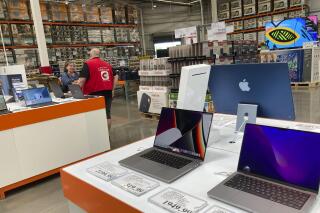 A sales associate helps a prospective customer as laptops sit on display in a Costco warehouse, Aug. 15, 2022, in Sheridn, Colo. Americans picked up their spending a bit in August from July even as surging inflation on household necessities like rent and food take a toll on household budgets. The U.S. retail sales rose an unexpected 0.3% last month, from being down 0.4% in July,  the Commerce Department said Thursday., Sept. 15, 2022. (AP Photo/David Zalubowski)