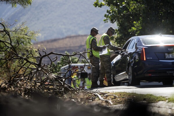 Members of the Hawaii National Guard check on a car passing the checkpoint on Kaniau Road, Monday, Sept. 25, 2023, in Lahaina, Hawaii. A small group of Lahaina residents returned to their devastated properties Monday for the first time since the Hawaii town was destroyed by wildfire nearly seven weeks earlier. (AP Photo/Mengshin Lin)