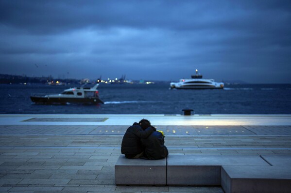 A couple embrace next to the Bosphorus during Valentine's Day in Istanbul, Turkey, Wednesday, Feb. 14, 2024. (AP Photo/Francisco Seco)