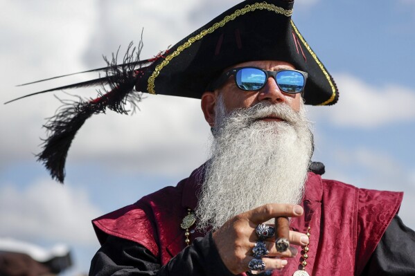 Robert Saliva, 53, of Tampa, smokes a cigar while taking in the festivities before the start of the Gasparilla Invasion on Saturday, Jan. 27, 2024, in Tampa. (Luis Santana/Tampa Bay Times via AP)