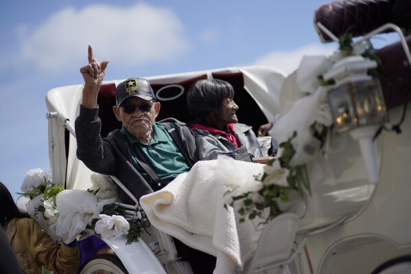 FILE - Tulsa Race Massacre survivors Hughes Van Ellis, left, and Lessie Benningfield Randle ride in a carriage at a remembrance walk during centennial commemorations of the Tulsa Race Massacre, May 28, 2021, in Tulsa, Okla. Van Ellis, who was the youngest known survivor of the Tulsa Race Massacre and who spent his latter years pursuing justice for his family and other descendants of the attack on “Black Wall Street,” died on Monday, Oct. 9, 2023. He was 102. (AP Photo/John Locher, File)