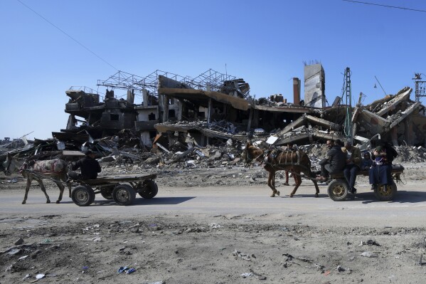 Palestinians ride on donkey carts through destruction from the Israeli bombardment at the main road of Salah el Dein in the Maghazi refugee camp, central Gaza Strip, Friday, Feb. 16, 2024. (APPhoto/Adel Hana)