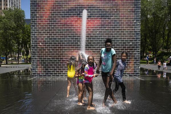 Children play in the Crown Fountain on Michigan Avenue, Tuesday afternoon, June 14, 2022, in Chicago. Much of the Midwest and a swath of the South braced for a potentially dangerous and deadly heat wave on Tuesday, with temperatures that could reach record highs in some places and combine with humidity to make it feel like it’s 100 degrees or hotter in spots. (Ashlee Rezin/Chicago Sun-Times via AP)