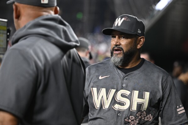 Washington Nationals manager Dave Martinez, right, talks with his coaches in the dugout during the eighth inning of a baseball game against the Los Angeles Angels, Saturday, Aug. 10, 2024, in Washington. (AP Photo/John McDonnell)