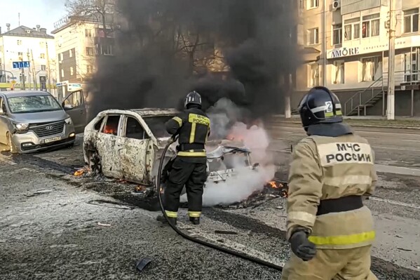 In this photo taken from video released by Russia Emergency Situations Ministry telegram channel on Saturday, Dec. 30, 2023, Firefighters extinguish burning cars after shelling in Belgorod, Russia. Russian officials have accused Ukrainian forces of shelling the Russian border city of Belgorod. Two children were killed in Saturday's attack, regional governor Vyacheslav Gladkov said in a statement on social media. He also said that an unspecified number of people had been injured. (Russia Emergency Situations Ministry telegram channel via AP)
