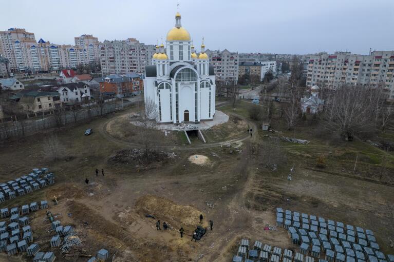 FILE - Journalists examine the site of a mass grave in Bucha, Ukraine, on the outskirts of Kyiv, Tuesday, April 5, 2022, after Russian forces left. (AP Photo/Rodrigo Abd, File)