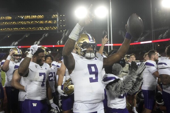 Washington quarterback Michael Penix Jr. (9) celebrates with teammates after the team's win over Stanford in an NCAA college football game in Stanford, Calif., Saturday, Oct. 28, 2023. (AP Photo/Jeff Chiu)
