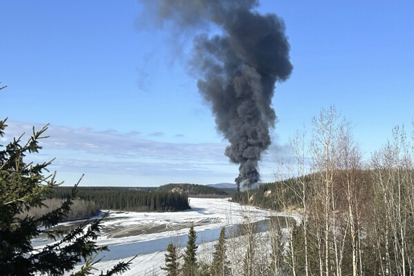 Smoke rises after a Douglas C-54 Skymaster plane crashed into the Tanana River outside Fairbanks, Alaska, Tuesday, April 23, 2024. The plane took off in the morning from Fairbanks International Airport. It crashed about 7 miles (11 kms.) from there and "slid into a steep hill on the bank of the river where it caught fire," according to Alaska State Troopers. (Gary Contento via AP)