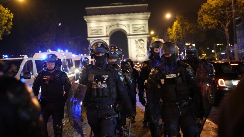 Police officers patrol in front of the Arc de Triomphe on the Champs Elysees in Paris, Saturday, July 1, 2023. President Emmanuel Macron on Saturday scrapped an official trip to Germany after a fourth straight night of rioting and looting across France in defiance of a massive police deployment. Hundreds turned out for the burial of the 17-year-old whose killing by police triggered the unrest. (AP Photo/Christophe Ena)