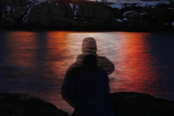 FILE - In this photo made with a long exposure, a man is silhouetted against lights reflected in the waters off Cape Neddick in Maine on Dec. 11, 2017. A study published Thursday, Sept. 14, 2023, in the journal Nature Medicine has found that the psychedelic drug MDMA, combined with talk therapy, can reduce symptoms of post-traumatic stress disorder. (AP Photo/Robert F. Bukaty, File)