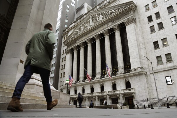 FILE — People pass the front of the New York Stock Exchange, March 22, 2023. The average Wall Street bonus fell slightly last year to $176,500 as firms took a “more cautious approach” to compensation, New York state’s comptroller reported Tuesday, March 19, 2024. (AP Photo/Peter Morgan, File)