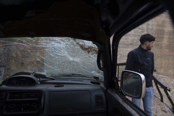 A youth inspects the wrecked truck of the 17-year-old Tawfic Abdel Jabbar, a teenager from Louisiana who was fatally shot last week, when he was driving in the family's Palestinian home village, Al-Mazra'a ash-Sharqiya, West Bank, Tuesday, Jan. 23, 2024. (AP Photo/Nasser Nasser)