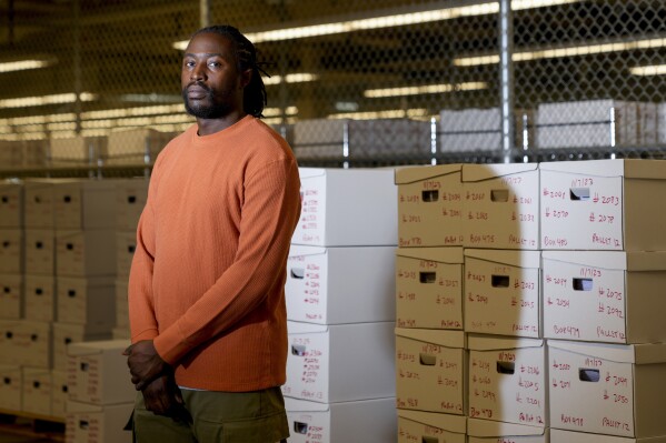 Ballot opening lead Eldon Miller poses for a portrait in front of boxes of processed ballots at the King County Elections headquarters, Friday, Nov. 17, 2023, in Renton, Wash. The office began stocking Narcan, the nasal spray version of overdose-reversal drug naloxone, after receiving a letter laced with fentanyl in the summer and was evacuated the day after Election Day after receiving a similar envelope. (AP Photo/Lindsey Wasson)