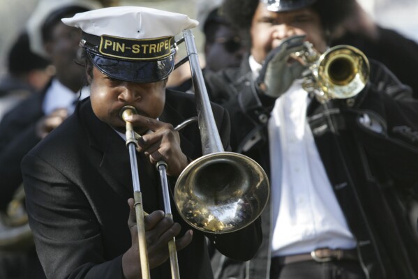 The band plays during the Zulu Social Aid & Pleasure Club's traditional Jazz Funeral to remember those who perished in Hurricane Katrina and aftermath, Feb. 11, 2006, on Jackson Ave. in New Orleans. (AP Photo/Mary Ann Chastain,file)