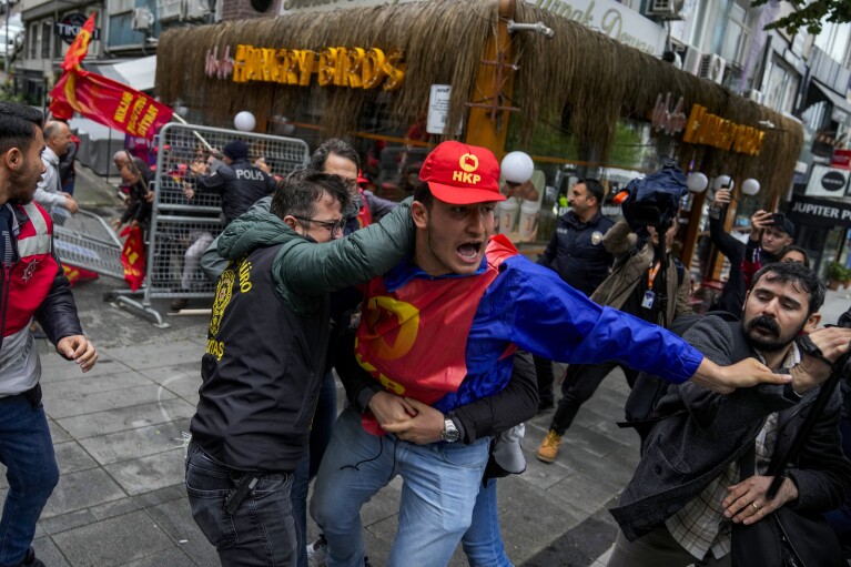 Um sindicalista briga com policiais à paisana enquanto caminha com outras pessoas durante as celebrações do Dia do Trabalho em Istambul, Turquia, quarta-feira, 1º de maio de 2024. (AP Photo/Khalil Hamra)