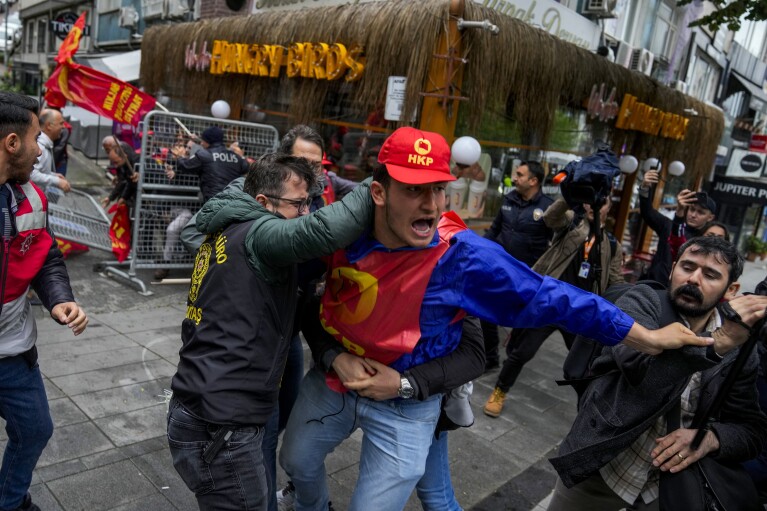 Een vakbondslid krijgt ruzie met de politie in burger terwijl hij met anderen wandelt tijdens de viering van de Dag van de Arbeid in Istanboel, Turkije, woensdag 1 mei 2024. (AP Photo/Khalil Hamra)