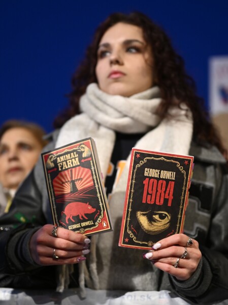 A woman holds books as thousands gather to oppose the policies of Slovakia's Prime Minister Robert Fico in Bratislava, Slovakia, Friday, Jan. 24, 2025. (AP Photo/Denes Erdos)