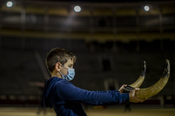 Pupil Nicolas Sanz Luna, 10, holds a pair of plastic bull horns at the Bullfighting School at Las Ventas bullring in Madrid, Spain, Tuesday, Dec. 22, 2020. At this school children as young as 9 can begin learning this deadly dance of human and beast so closely associated with Spanish identity. The school was closed from March to August when Spain went into one of the world's strictest confinements to stem the spread of the COVID-19 pandemic.(AP Photo/Manu Fernandez)