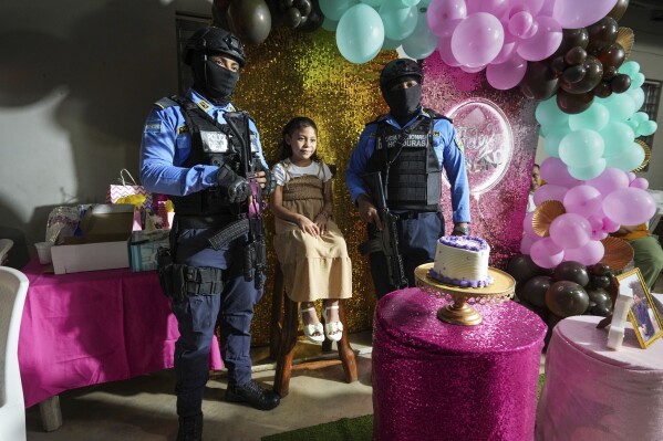 Julia Lopez Peña, the daughter of slain environmentalist Juan López, poses for a photo with her state-assigned bodyguards at her ninth birthday party in Tocoa, Honduras, Saturday, Dec. 7, 2024. (AP Photo/Moises Castillo)