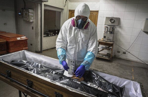 FILE - An employee takes the fingerprints of a woman who died from the new coronavirus before her remains are cremated at La Recoleta crematorium in Santiago, Chile, Saturday, June 27, 2020. Countries are still struggling to come up with an agreed-upon plan for how the world might respond to the next global outbreak. A ninth and final round of talks involving governments, advocacy groups and others to finalize a “pandemic treaty” is scheduled to end Friday, May 10, 2024. (AP Photo/Esteban Felix, File)