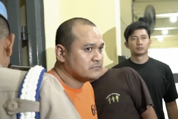 In this undated image made from video provided by Kompas TV, Indonesian police officers escort Thai fugitive Chaowalit Thongduang in Jakarta, Indonesia. Indonesian and Thai authorities said Monday, June 3, 2024, they will escort back Thailand's most wanted fugitive who was arrested on Indonesia’s tourist island of Bali after months on the run in connection with drug trafficking and several killings in his homeland. (Kompas TV via AP)