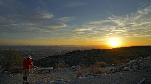 A hiker photographs the sun rising over the Valley atop South Mountain, Monday, July 17, 2023 Phoenix. Phoenix is set to break its own record for consecutive days of highs of at least 110 degrees. Around one-third of Americans are under some type of heat advisory, with the most blistering temperatures in the South and West, where even the regular simmer has turned up a notch. (AP Photo/Matt York)