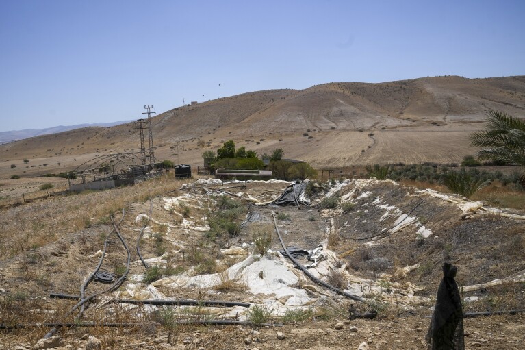 A dried water basin is seen near the Palestinian village of Bardala in the Jordan Valley Monday, Aug. 7, 2023. In the occupied West Bank, where Israeli water pipes don’t reach, Palestinians say they can't get enough water to irrigate their farms. By comparison, the neighboring Jewish settlements look like an oasis with swimming pools. (AP Photo/Mahmoud Illean)